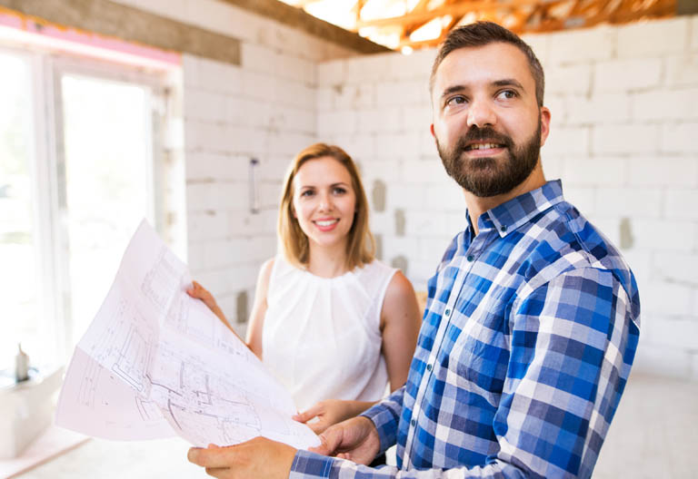 Paar mit Bauplan auf einer Baustelle